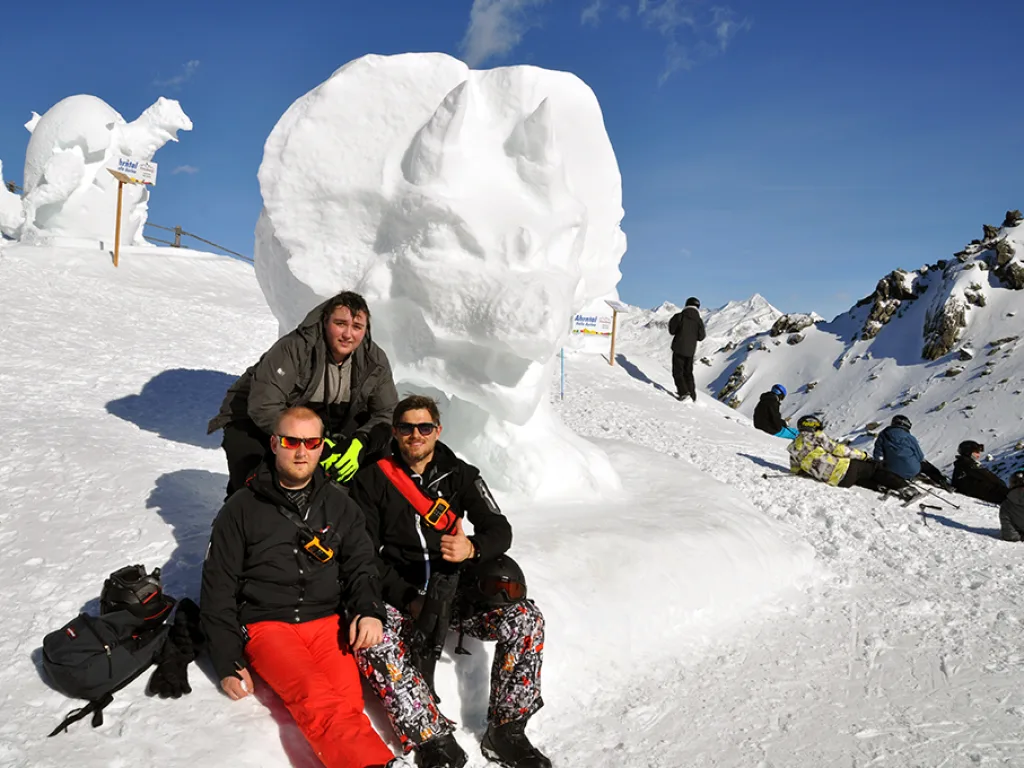 Zwei Personen posieren vor einer großen Schneeskulptur.